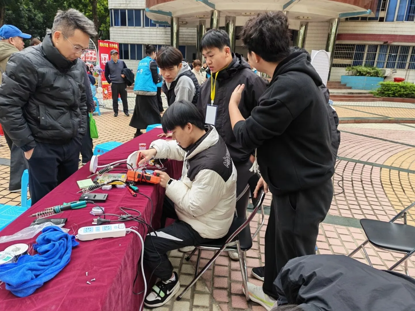义务维修服务点旁，学生围在维修桌前